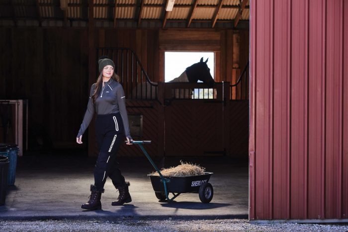 Woman bringing hay into a stable
